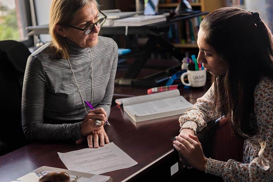 An advisor speaks with a student in her office.