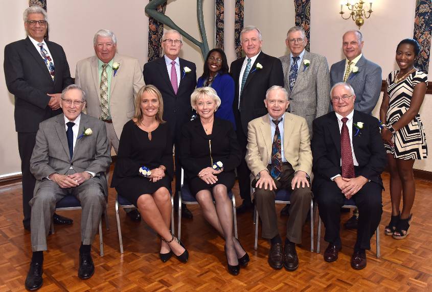 A group of men and women pose for a photo inside.