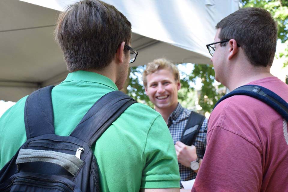 Three students in a group outdoors talking