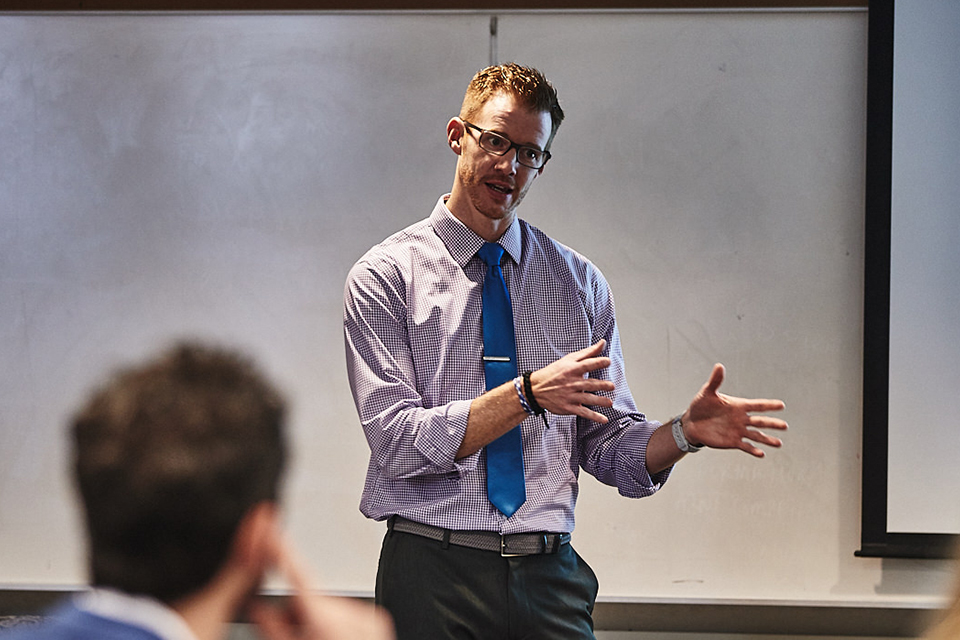 Brad Carlson, Ph.D., stands in front of a dry erase board with marker in-hand, teaching a class in the Chaifetz School of Business.