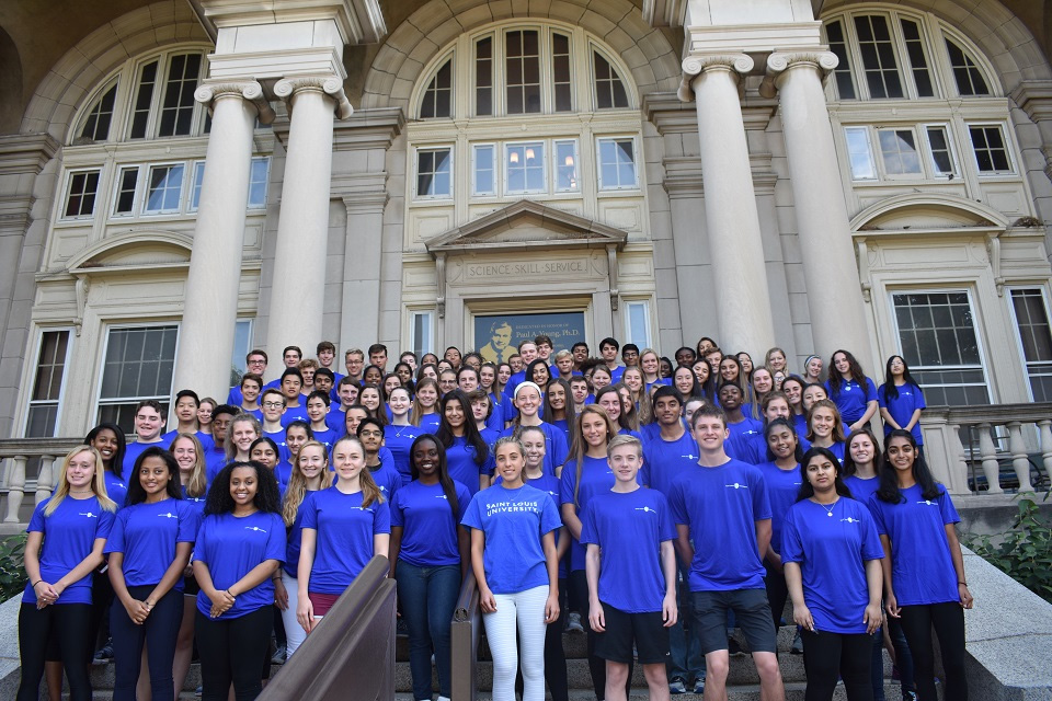 A group of about 60 AIMS summer workshop participants standing on the stairs posed for a group photo