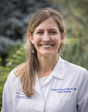 Headshot Program Director of Elizabeth Keegan Garrett. She wears a white coat and a red turtleneck sweater.