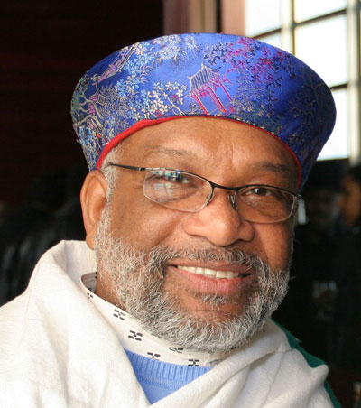 Photographer Chester Higgins dons a white shawl and a low-profile hat with sapphire-blue silk in a pagoda motif